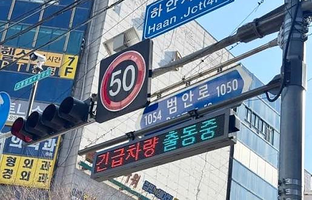 교차로에 설치된 긴급차량 출동안내 전광판 — '긴급차량 출동중' 표출